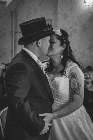 A steampunk-themed wedding couple share a romantic kiss during their ceremony.