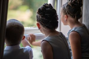 Three people gazing out a window together in a candid moment.