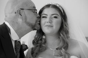 A tender wedding moment captured in black and white with a sparkling tiara and veil.