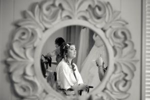 Wedding preparation reflected in ornate white baroque mirror frame.