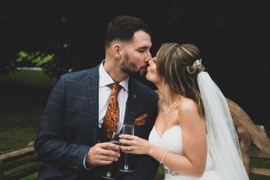 Newlyweds share champagne and an intimate moment in an outdoor setting.