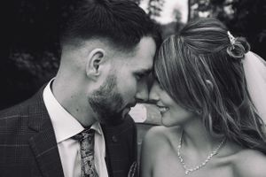 An intimate black and white portrait of newlyweds touching foreheads.