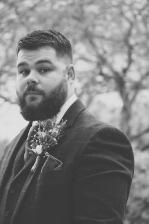 Black and white portrait showing groom in formal attire with boutonniere.