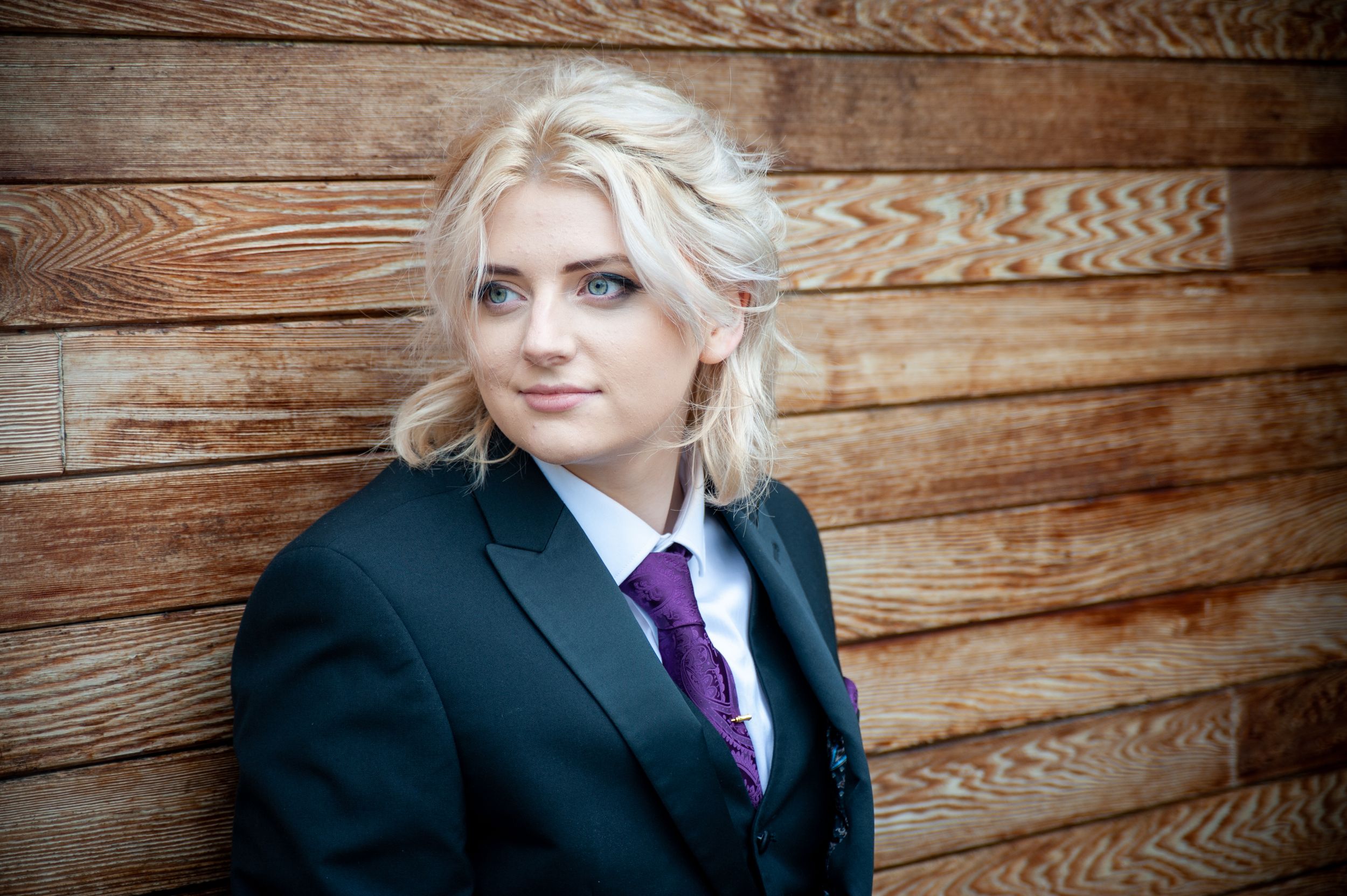 Professional portrait against wooden wall background with purple accent tie.