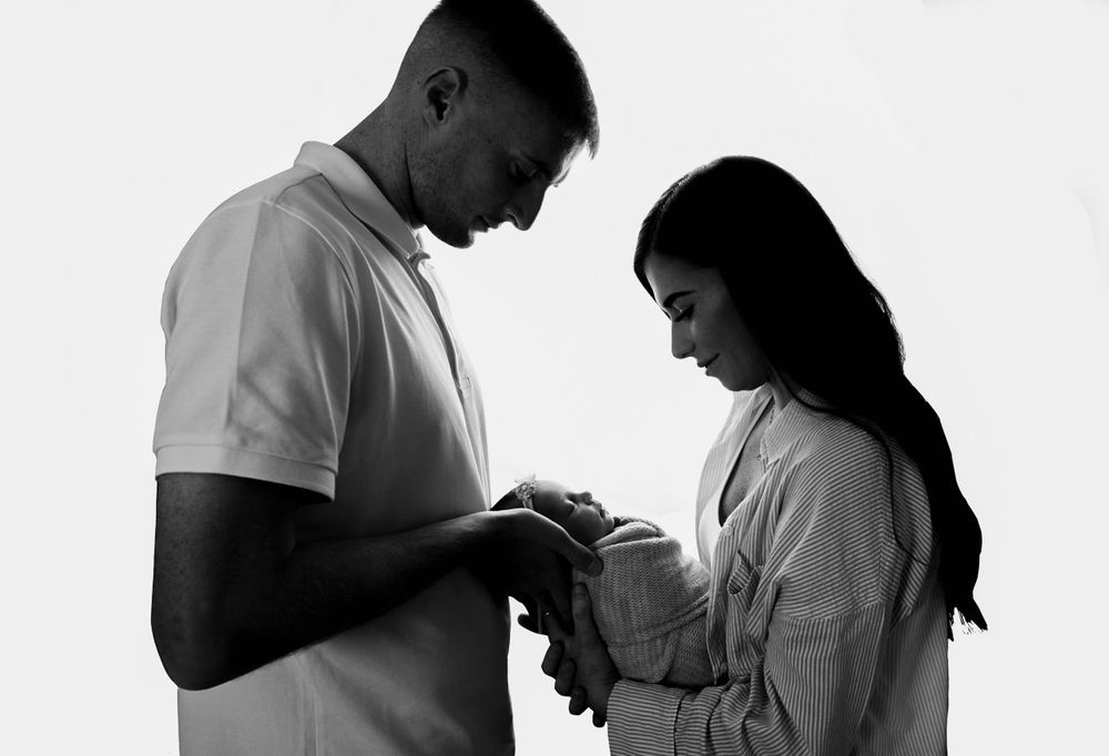 backlit parents shot with baby in parents hands