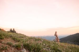 A scenic mountain vista with wildflowers blooming along the hiking trail at sunset.