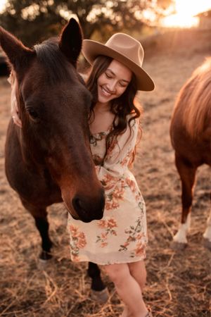 Tender moment between a horse and someone in a floral dress during golden hour.