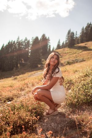 Golden hour portrait on mountainside with sunlit pine forest backdrop.