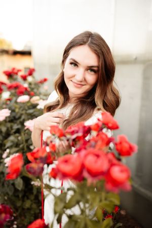 Red roses bloom in front of soft portrait with warm lighting and gentle smile.