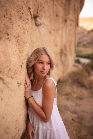 Portrait against orange canyon walls wearing a white summer dress at golden hour.