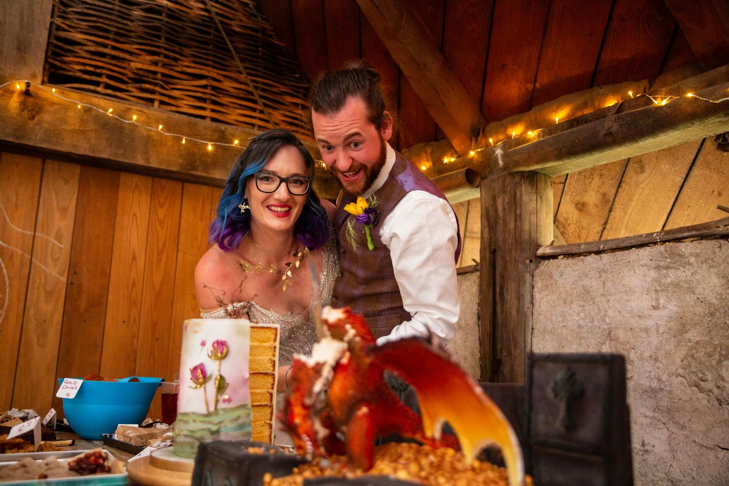 Cozy barn wedding reception with string lights and wooden beams creating warm ambiance.