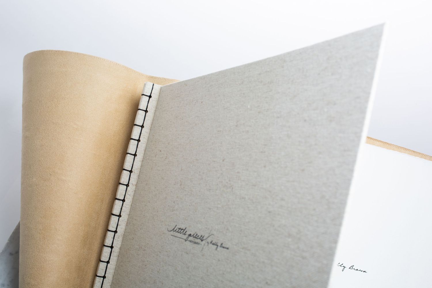 Open handmade book showing coptic stitch binding and textured gray cover.