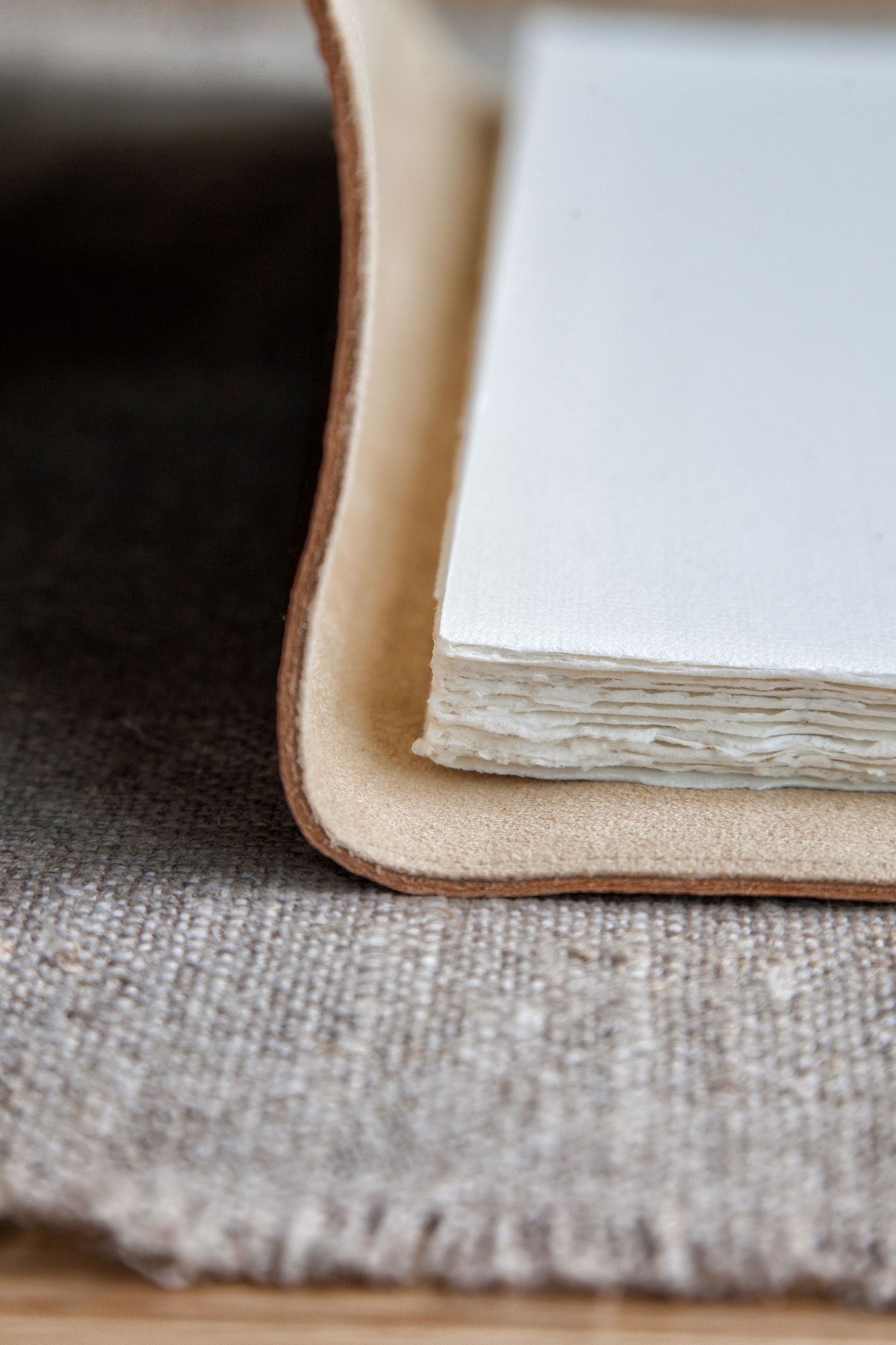 Macro detail of leather bound book edge showing layered white pages and textured fabric.