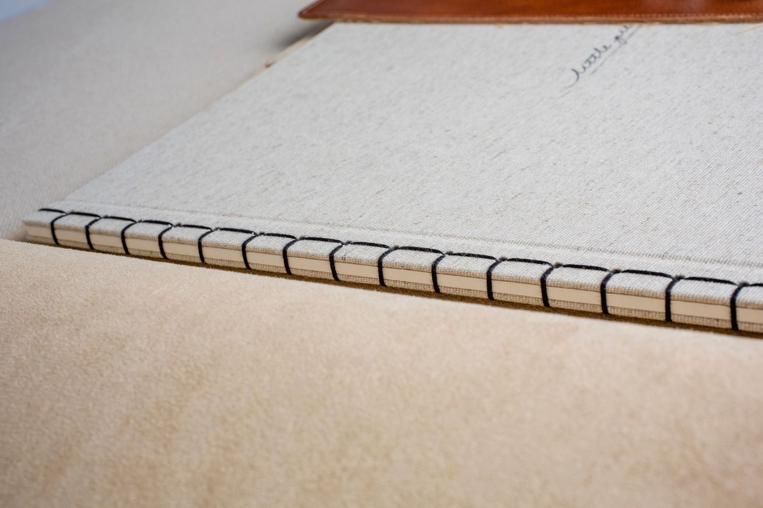 Close-up of handmade book binding showing detailed stitching pattern on cream colored paper.