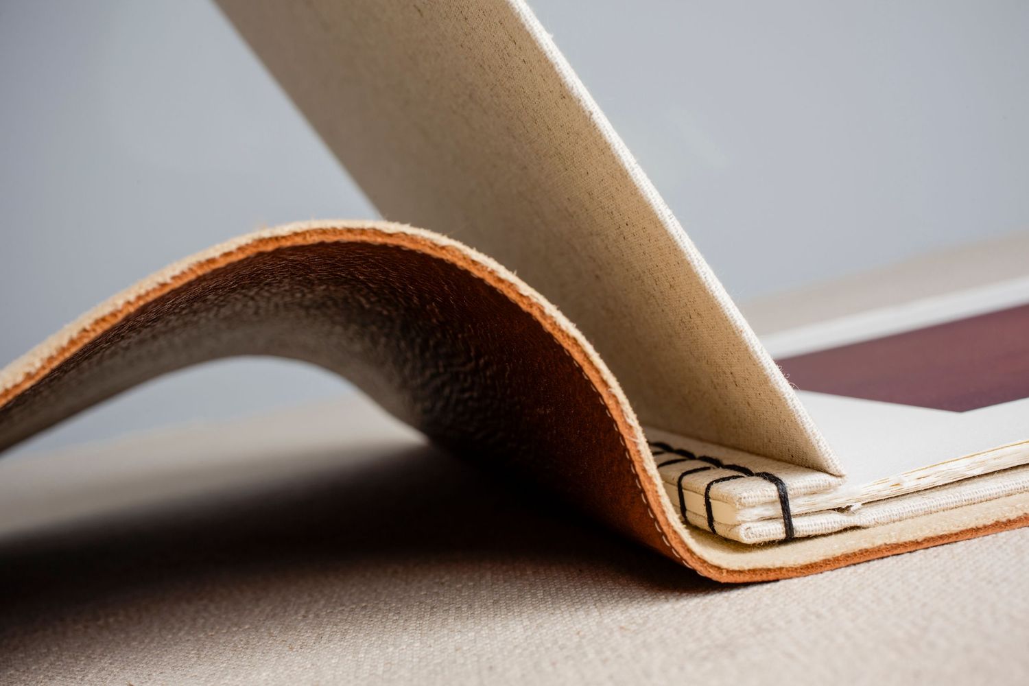 Curved leather binding detail showing bookmaking craftsmanship and stitching.