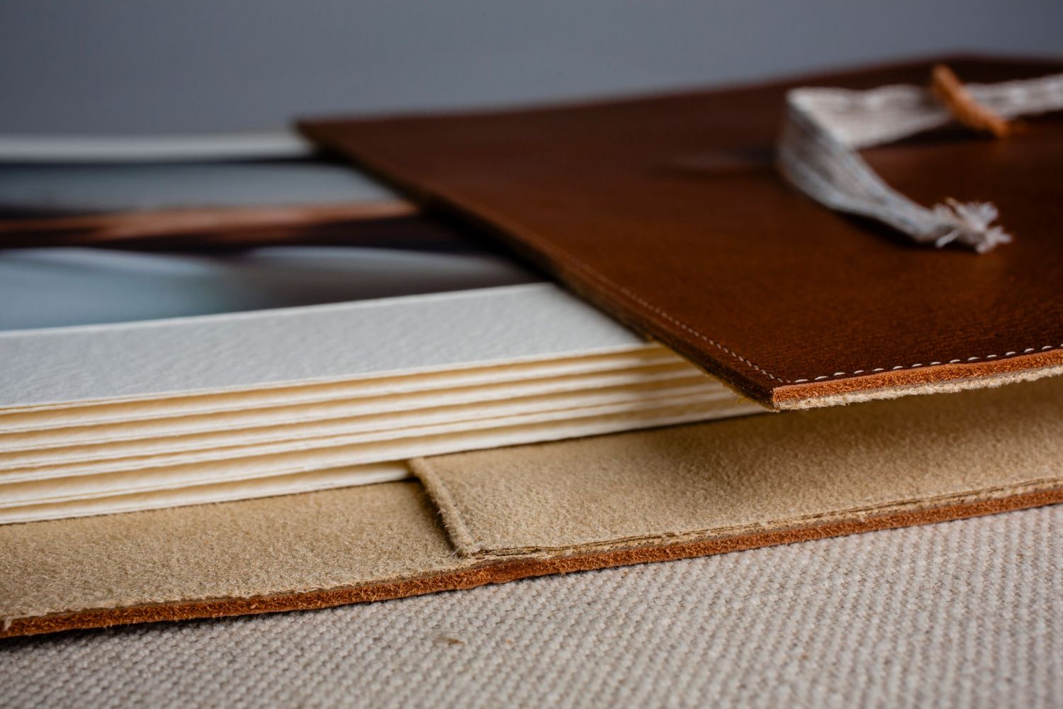 Brown leather portfolio with exposed binding showing multiple layers and stitching detail.