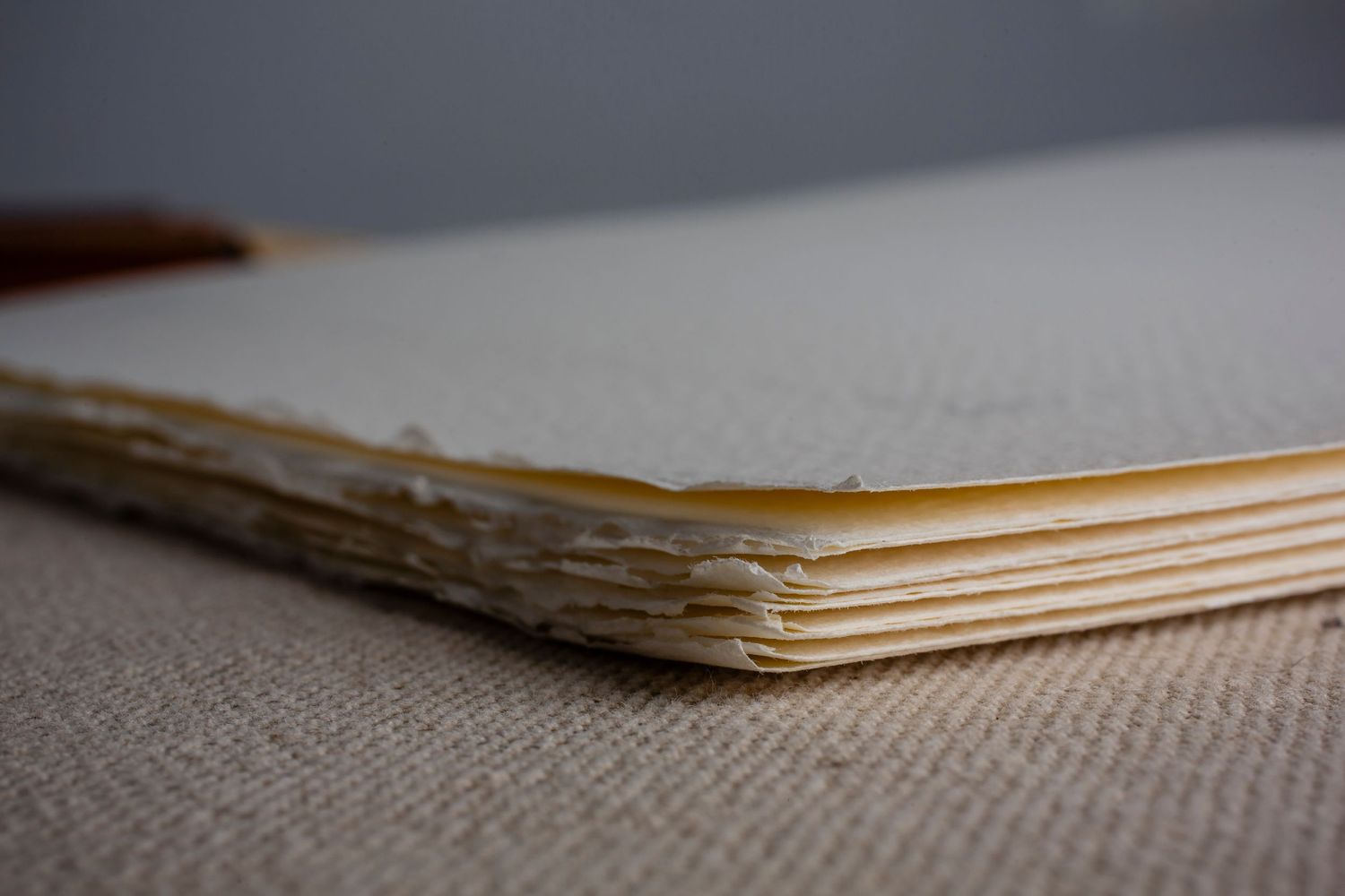 Side view of handmade book showing deckled edges of layered paper pages.