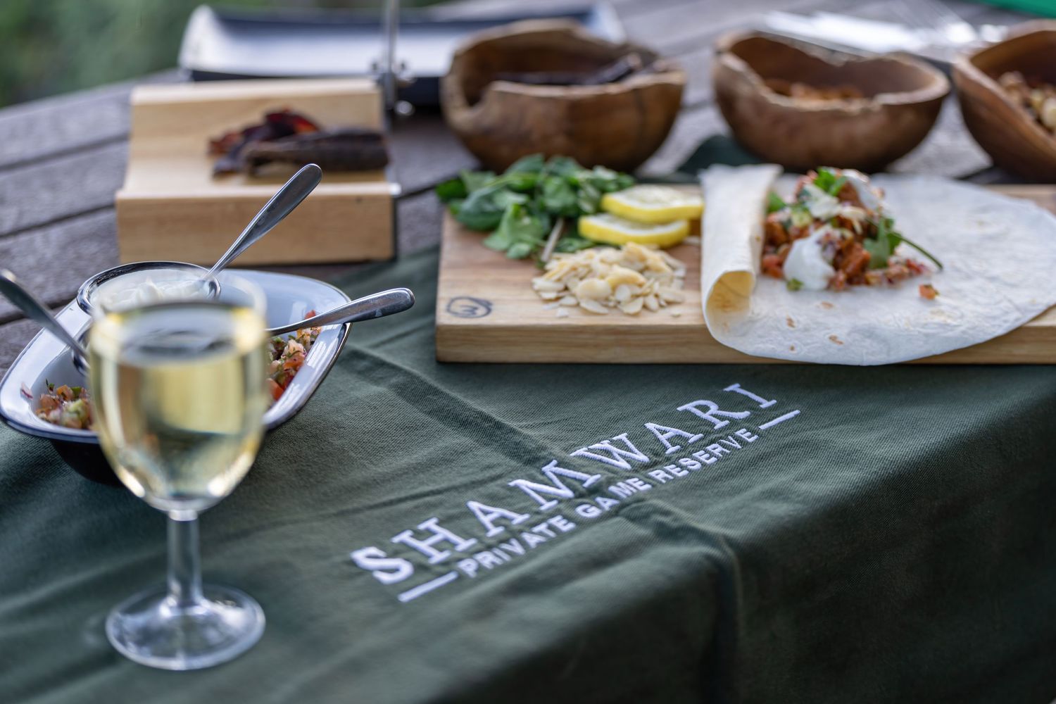 Elegant table setting with wine glasses and wooden serving boards displaying the Shamwari brand.