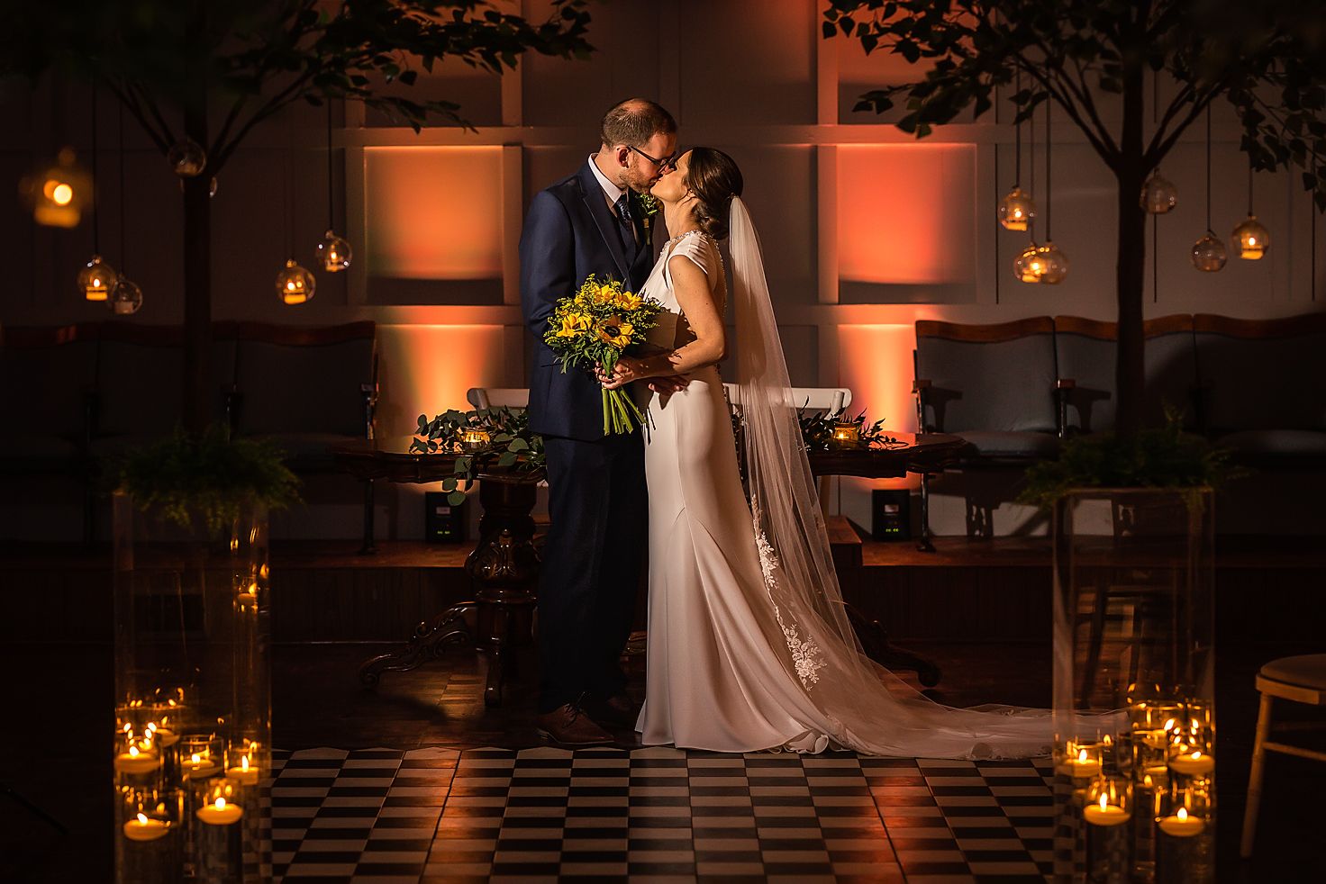 Bride and groom stand kissing in a dark candle lit wedding ceremony room at Larkspur Lodge in Cheshire
