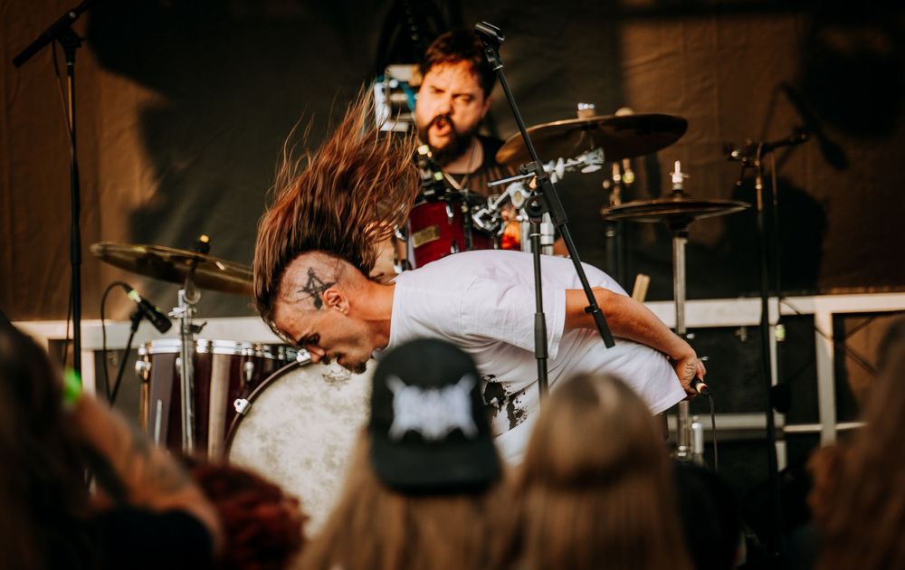 Energetic concert scene with performers and crowd during an intense musical moment.