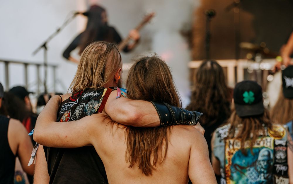 Concertgoers embracing during a live music performance with stage lights in the background.