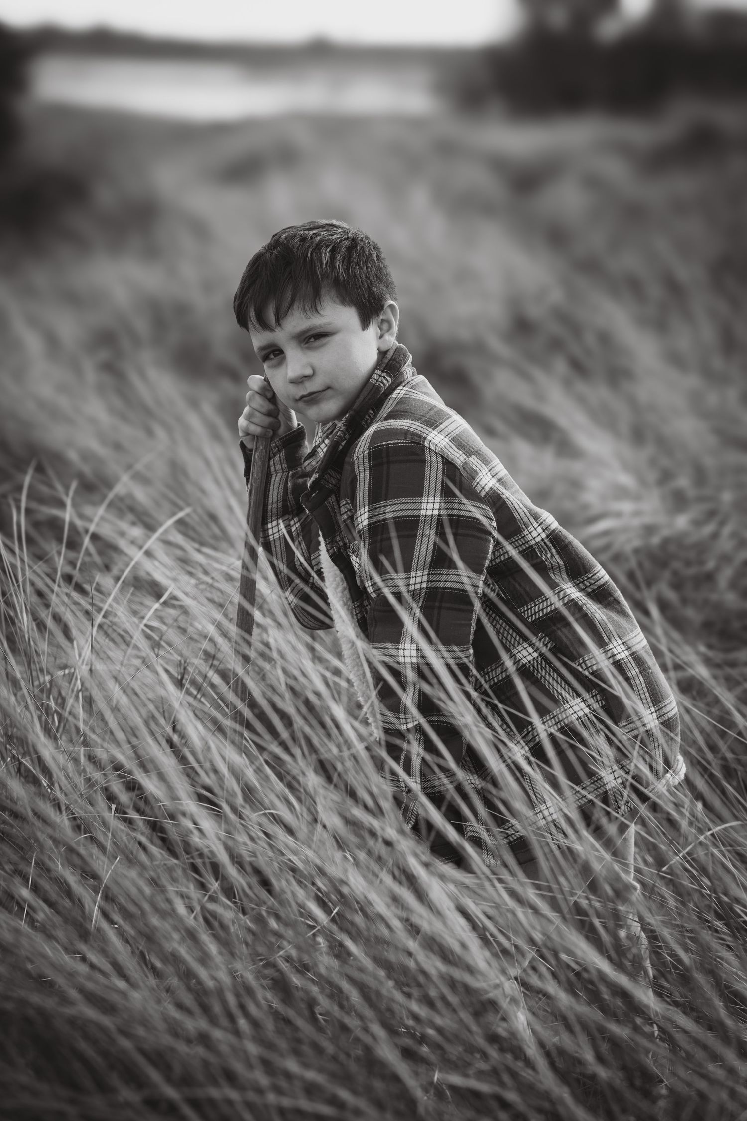 Artistic black and white portrait in tall grass shows contemplative mood.