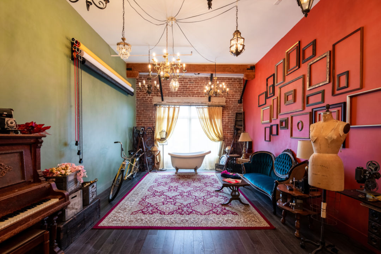 Victorian-style music room with piano, colorful walls, and vintage decor featuring ornate chandelier.