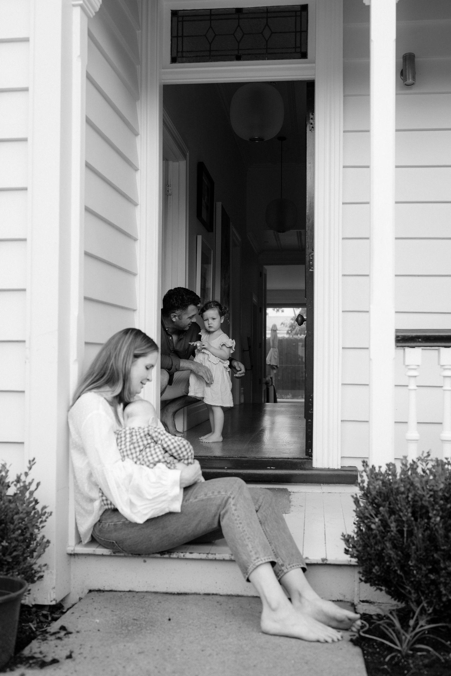 in home doorstep mother and father cuddling kids.  Natural family photos in Ponsonby Auckland