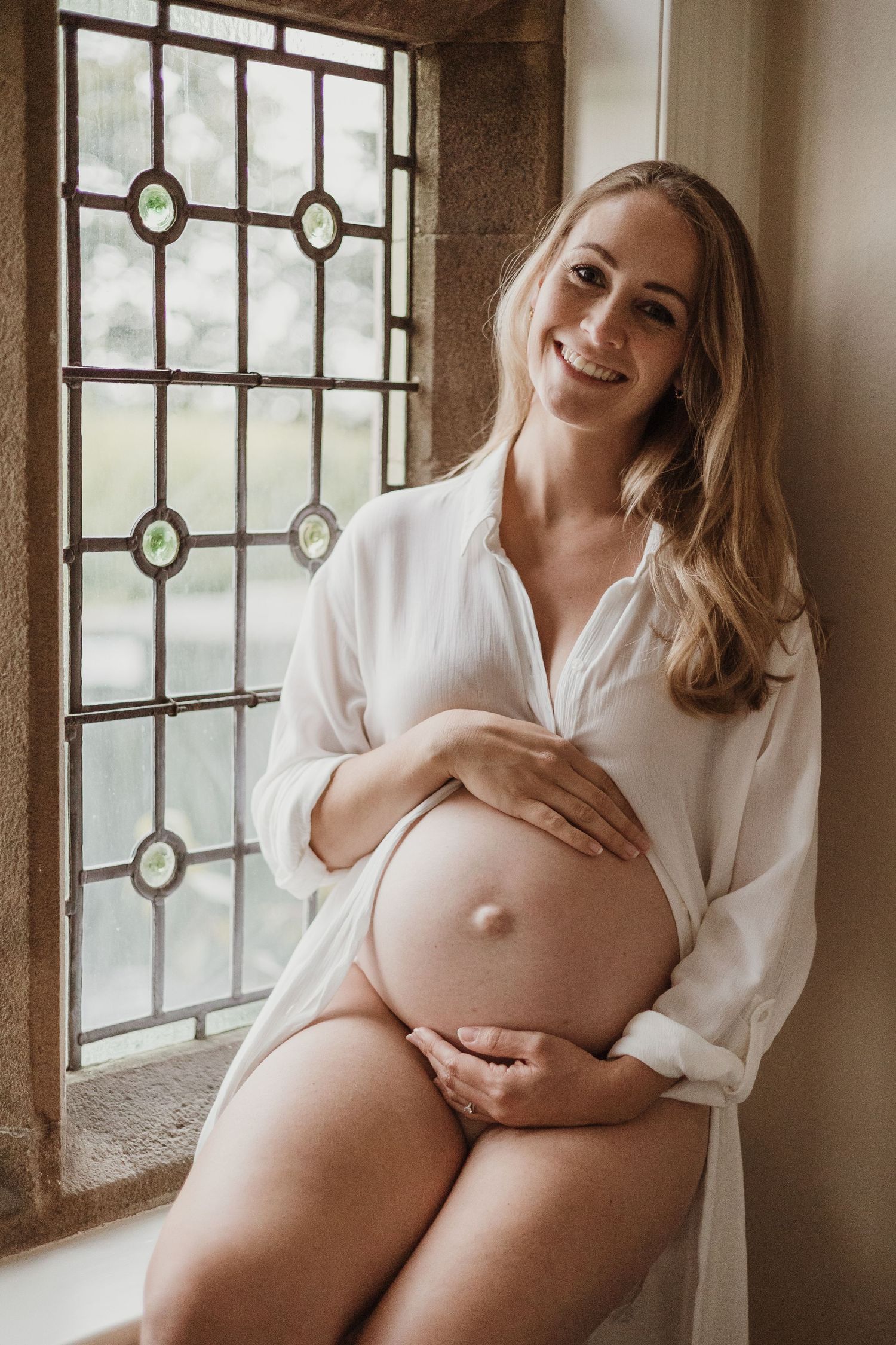 pregnant lady smiling sat in a stained glass window