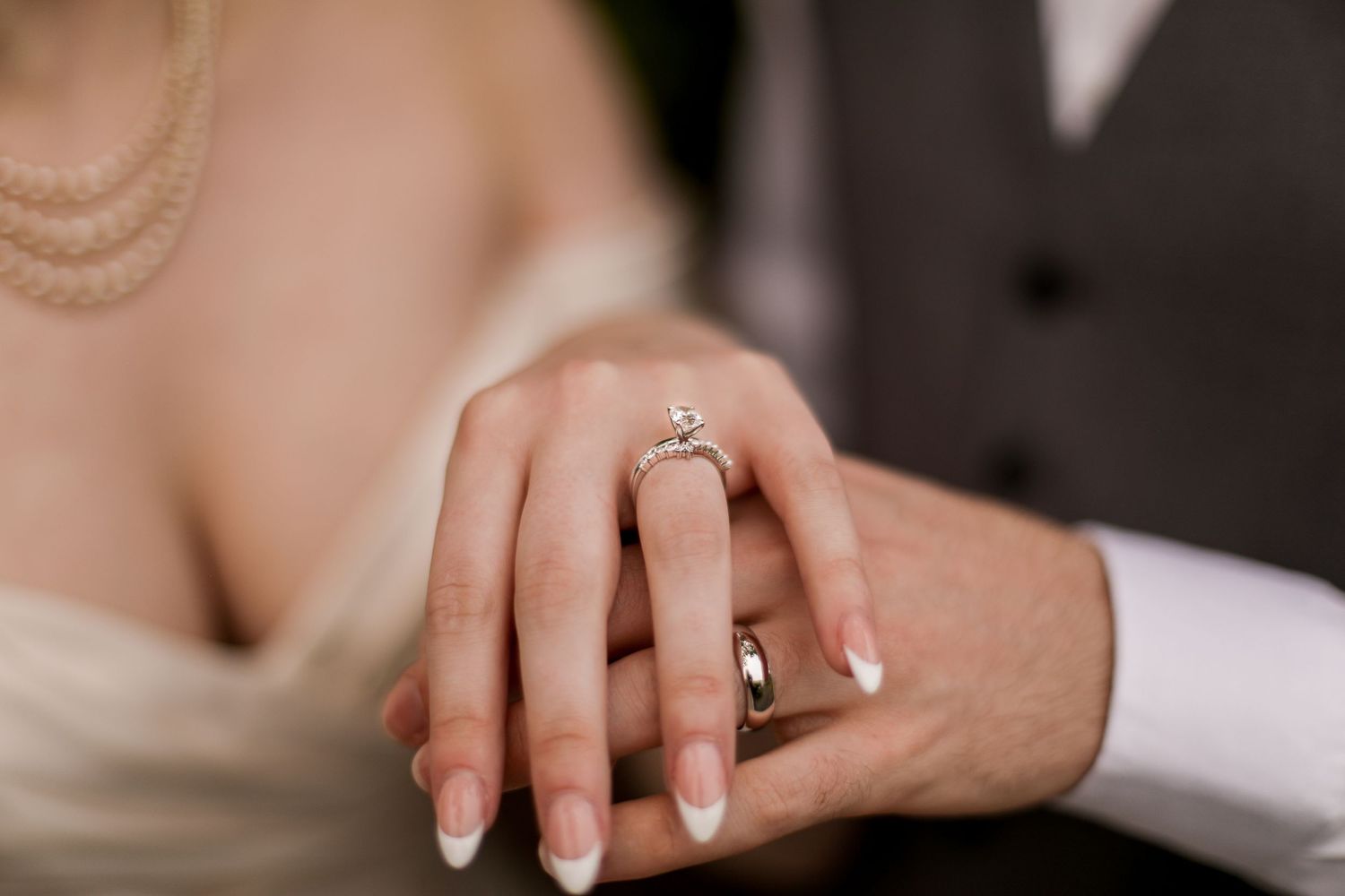 Close-up of wedding rings and hands showing the bride's engagement ring and manicure.