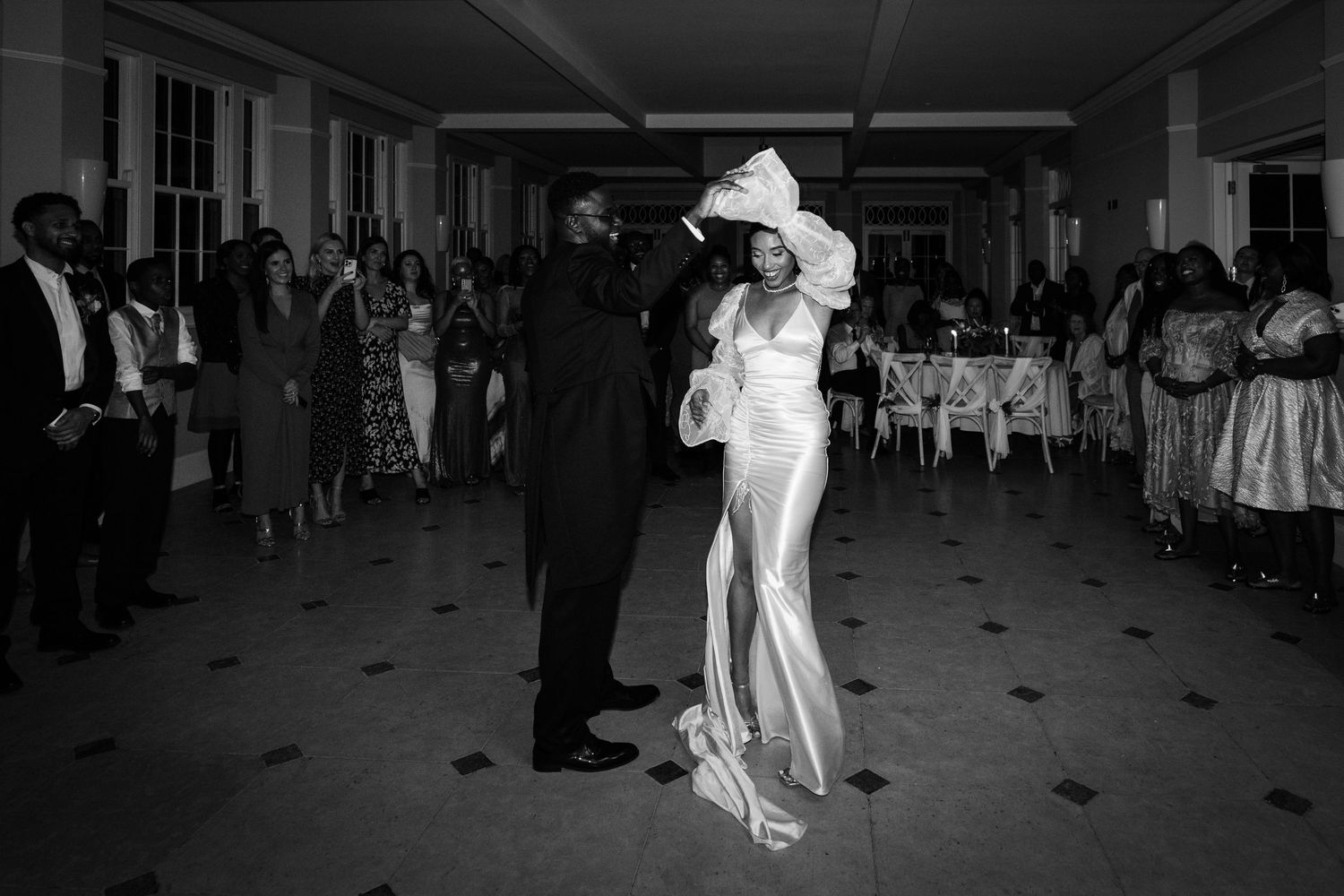 A couple dances at their wedding reception, with the bride wearing a sleek white gown.