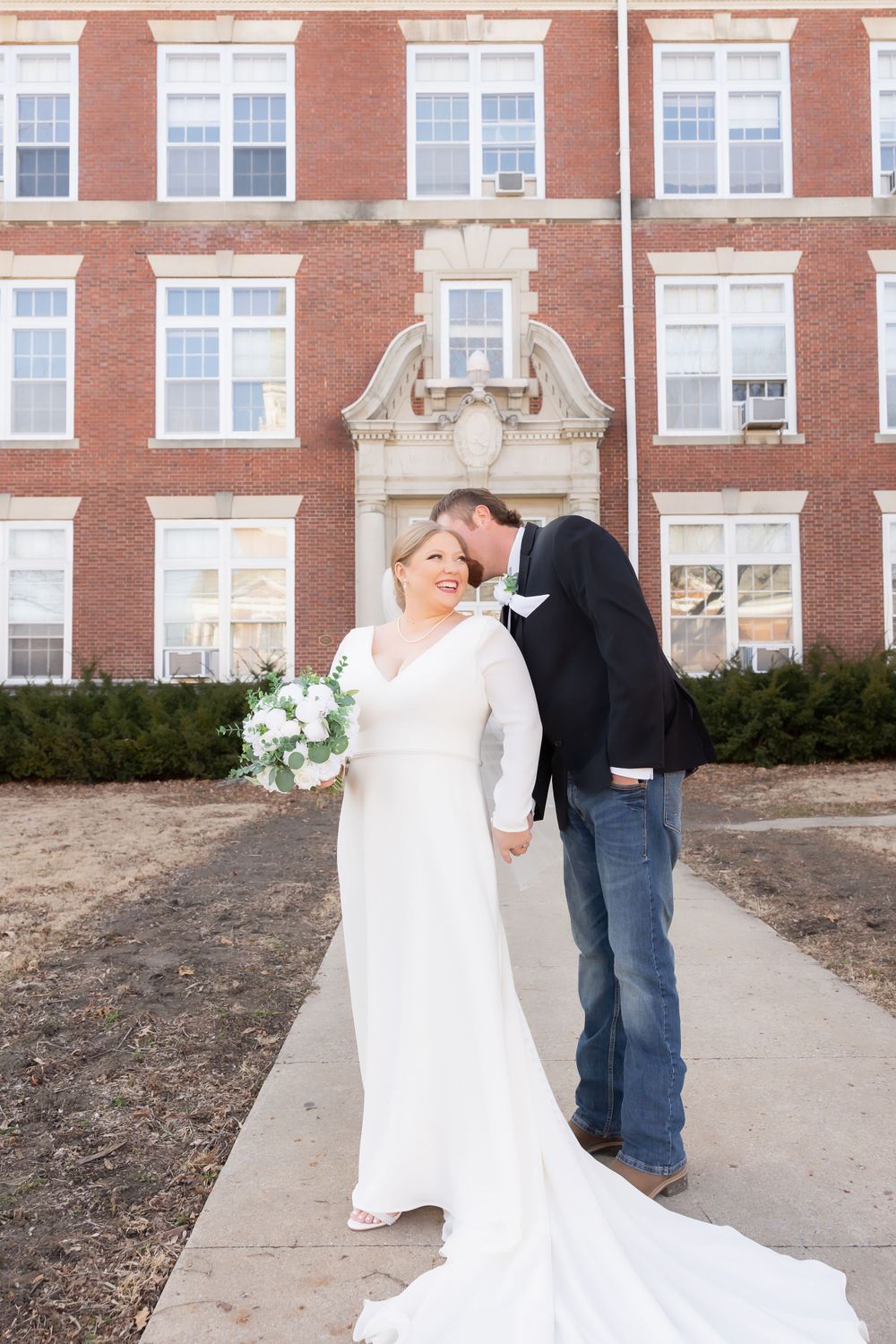 Elegant wedding portrait showcasing a long train white dress against classic brick architecture.