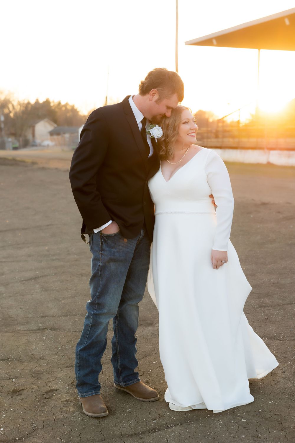 Golden hour wedding photo with couple sharing intimate moment against sunset backdrop.