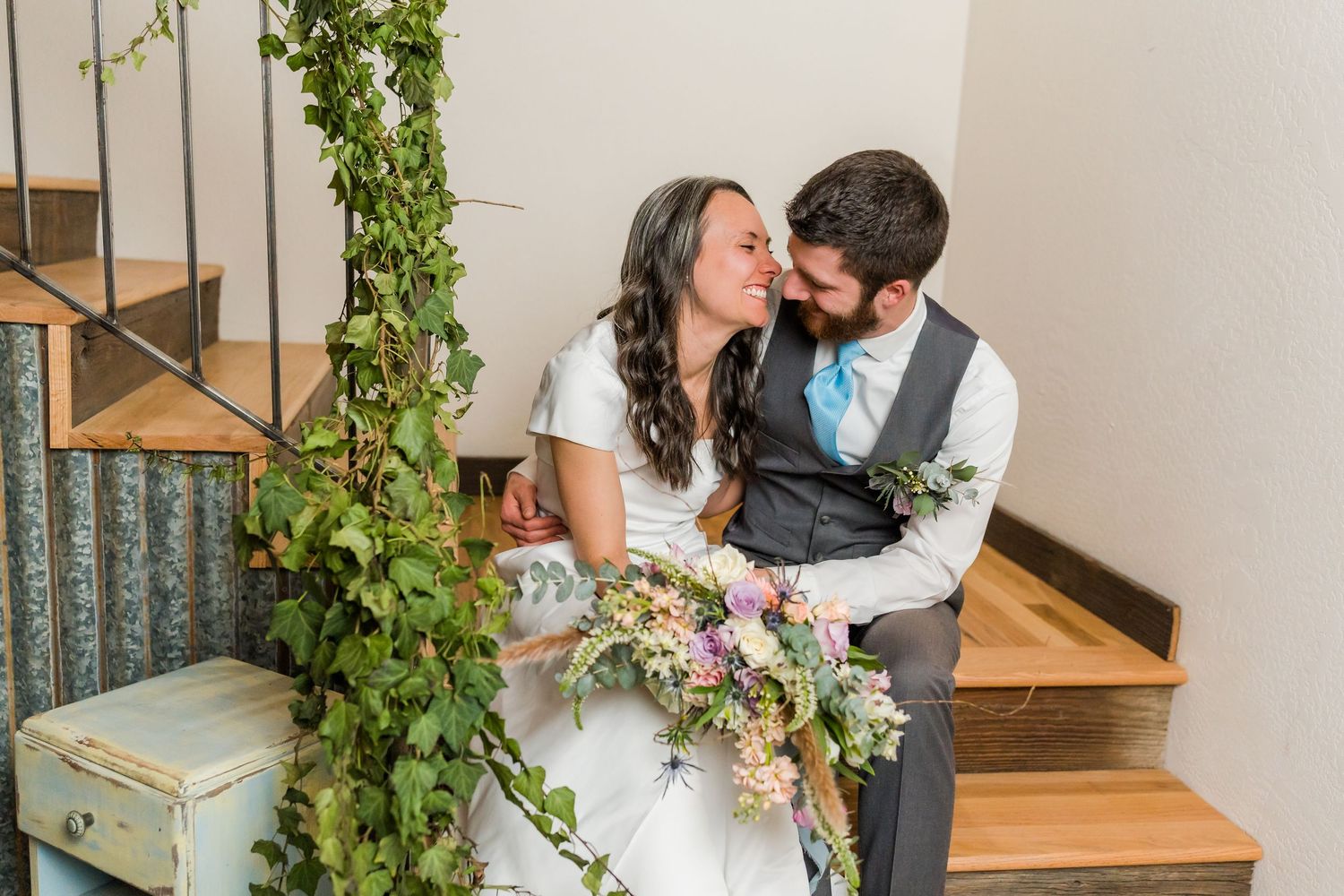 bride and groom sit on the stairs and laugh together