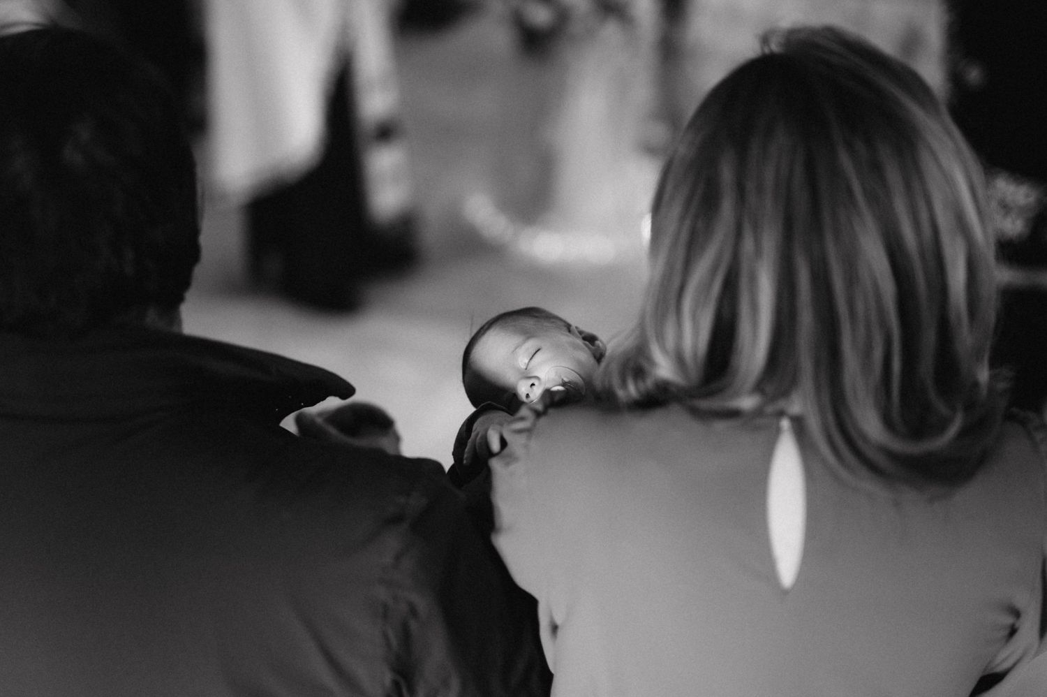 Black and white photo of a baby being held during a ceremony.