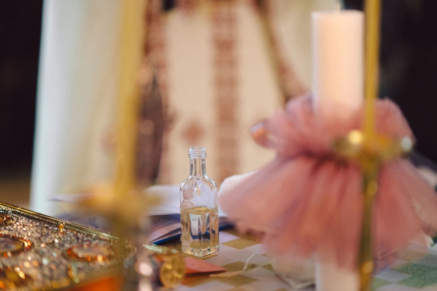 Close-up of decorative glass bottle and pink tulle on elegant table setting.