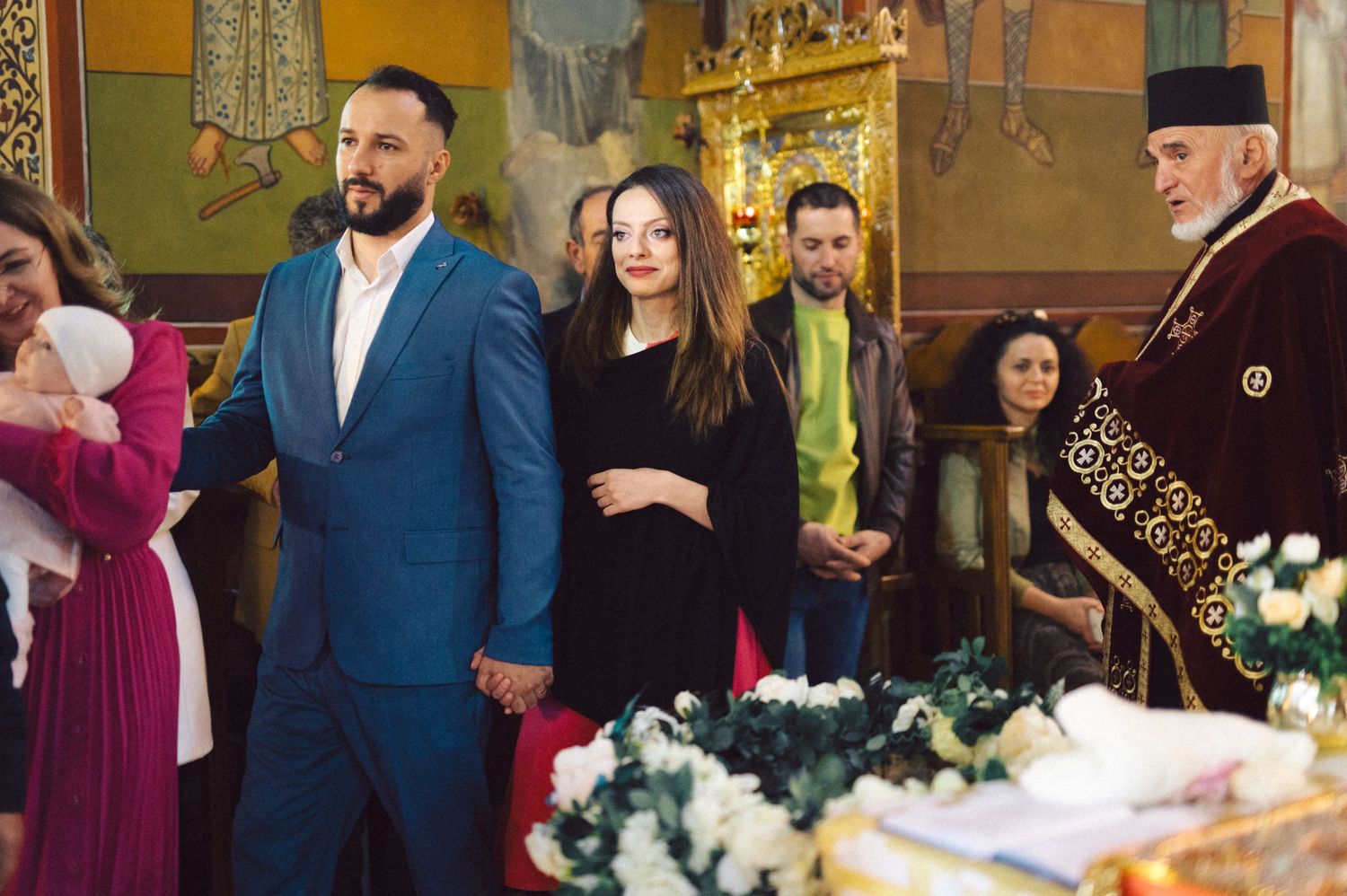 A group gathering inside an ornate church with golden decorations and floral arrangements.