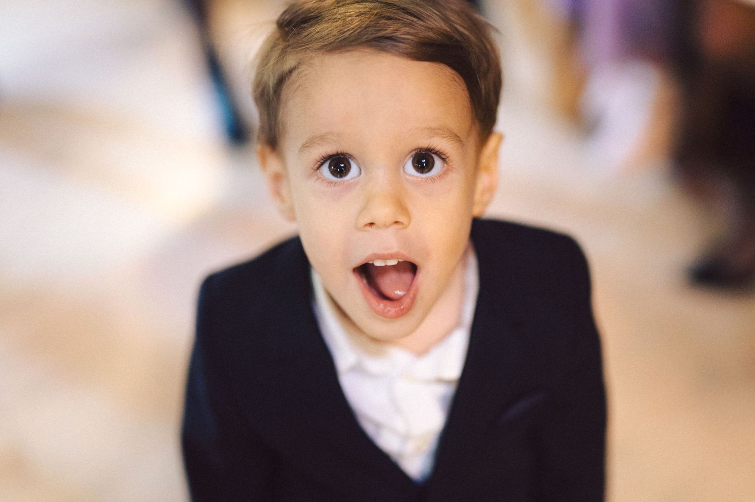 A young child in formal attire making an excited expression.