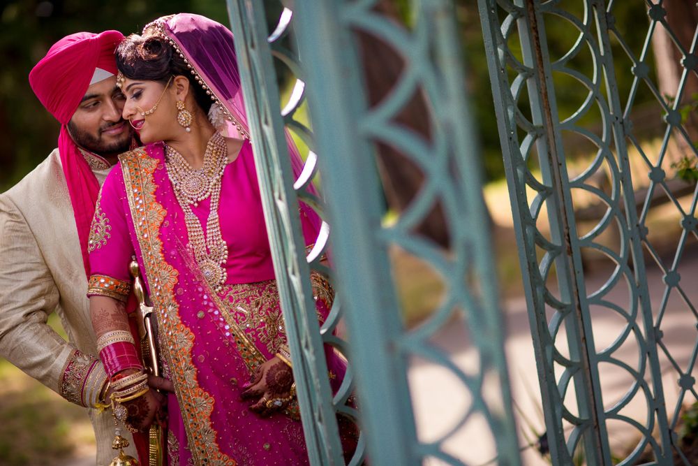 Couple in traditional Indian wedding attire sharing an intimate moment by decorative railings.