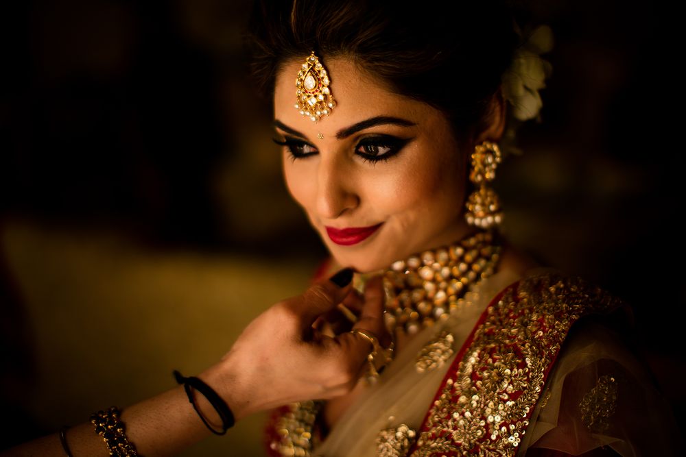 Close-up of intricate bridal jewelry and makeup in warm golden lighting.