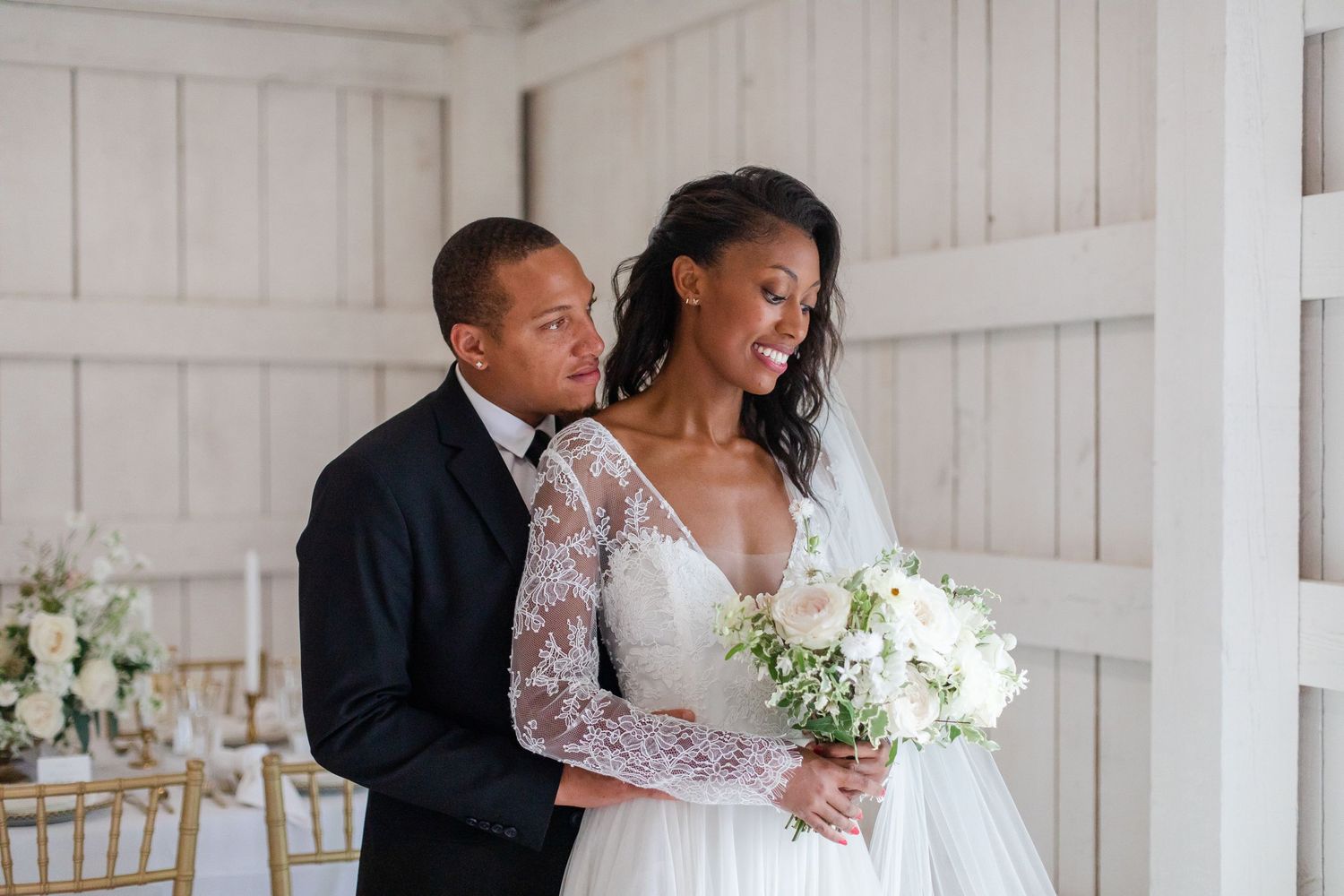 Wedding couple sharing an intimate moment against a white wooden wall backdrop.