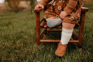 Brown leather boots and white socks detail shot on wooden chair.