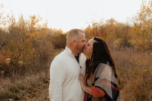 Couple embracing in a golden autumn field during sunset.