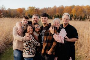 Extended family gathering for outdoor portrait session in fall field.