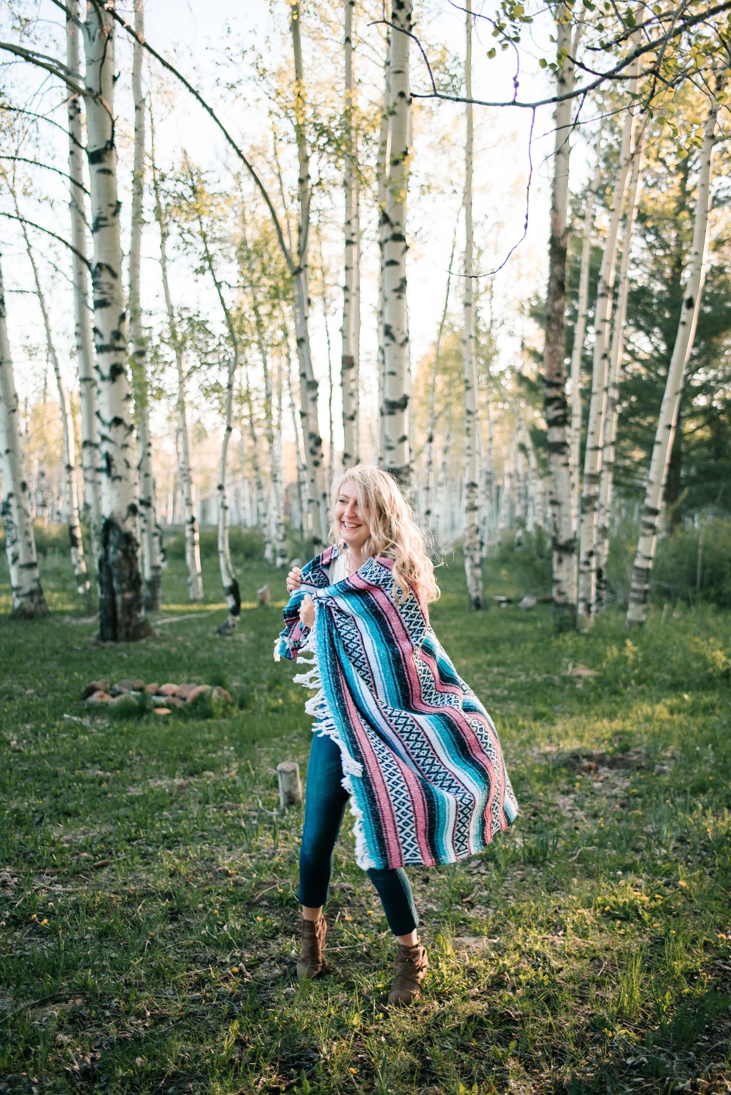 Dancing with a colorful Mexican blanket among white aspen trees in a forest setting.