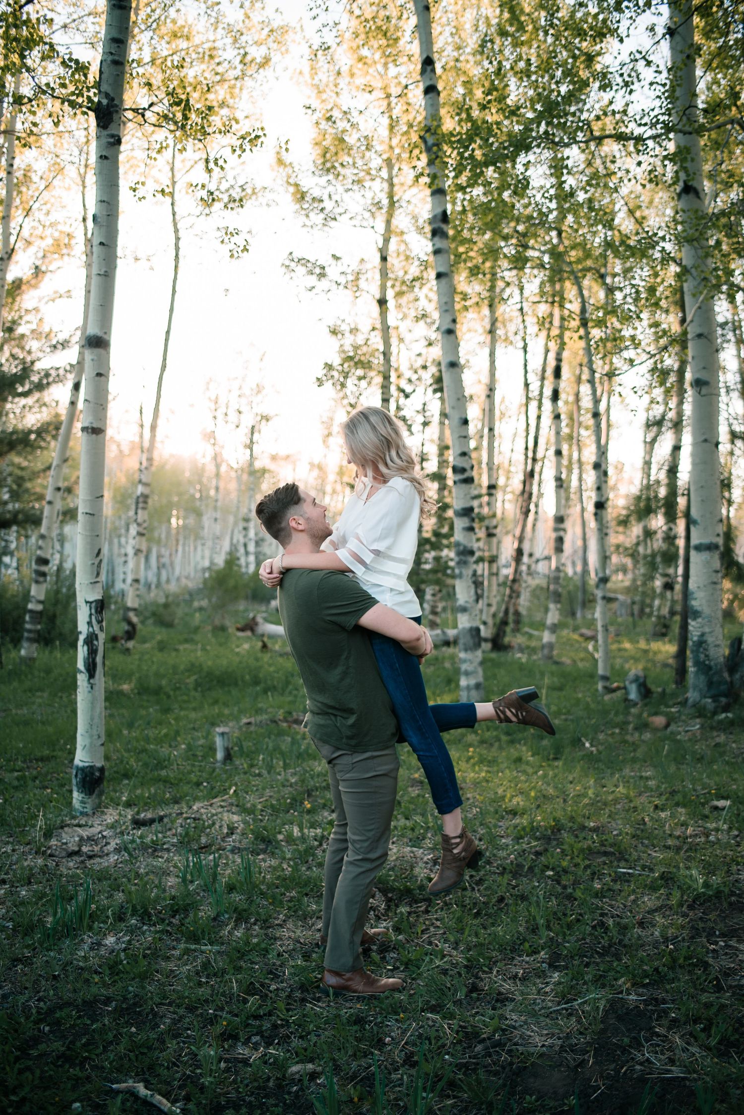 A playful couple spins and dances among a grove of birch trees.