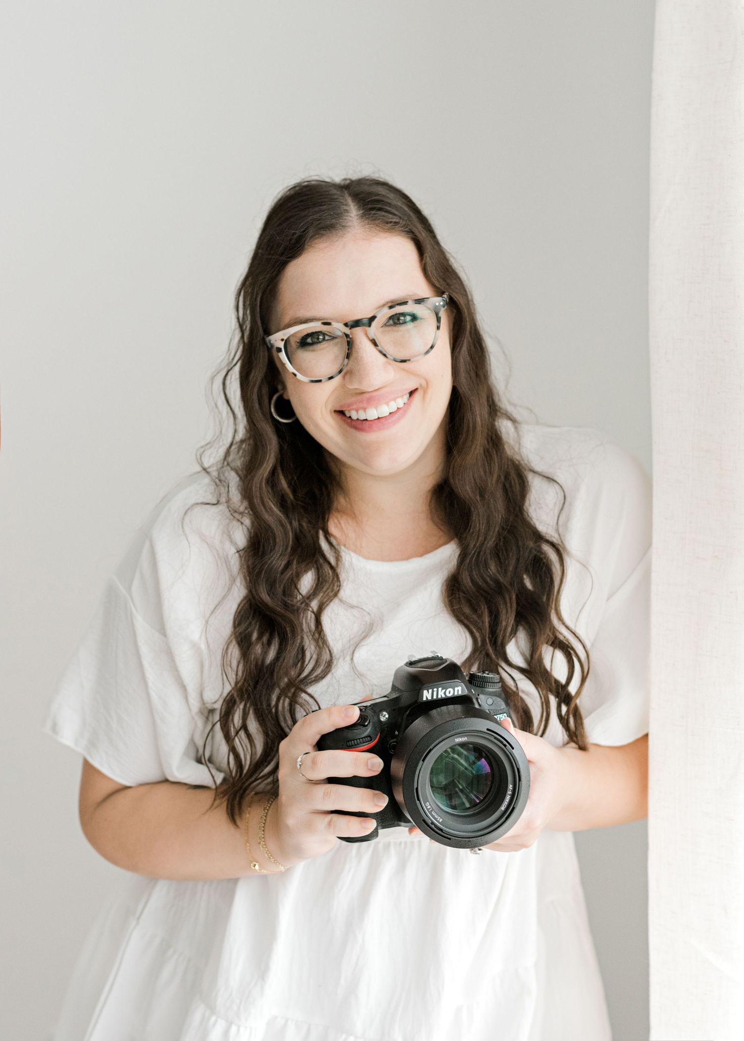 Austin, TX photographer holding her camera while smiling at camera
