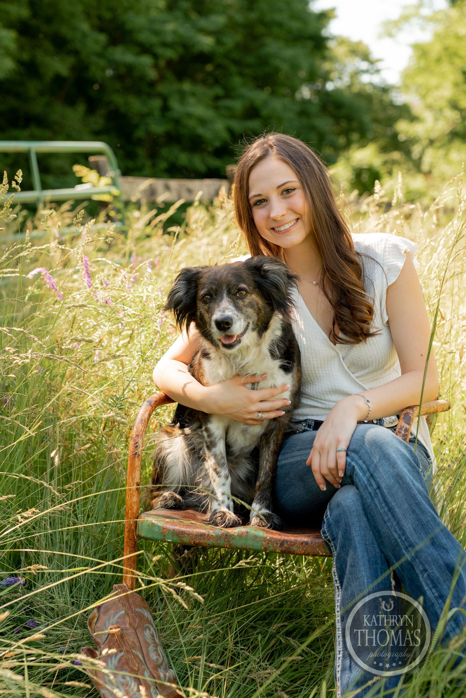Casual portrait with friendly dog on rustic chair surrounded by wildflowers and natural scenery.