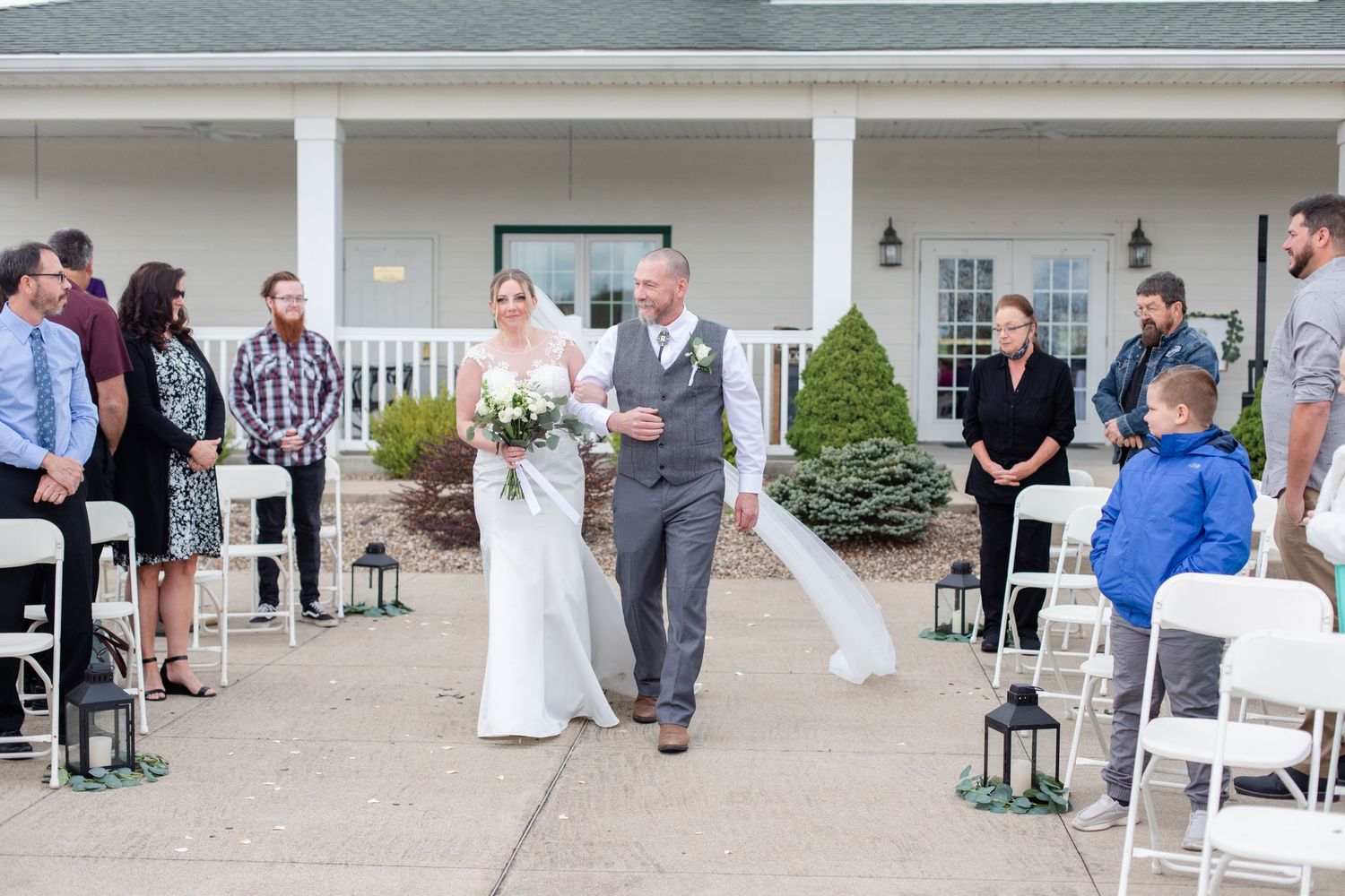 Wedding guests and party members gather outside a white columned venue during celebration.