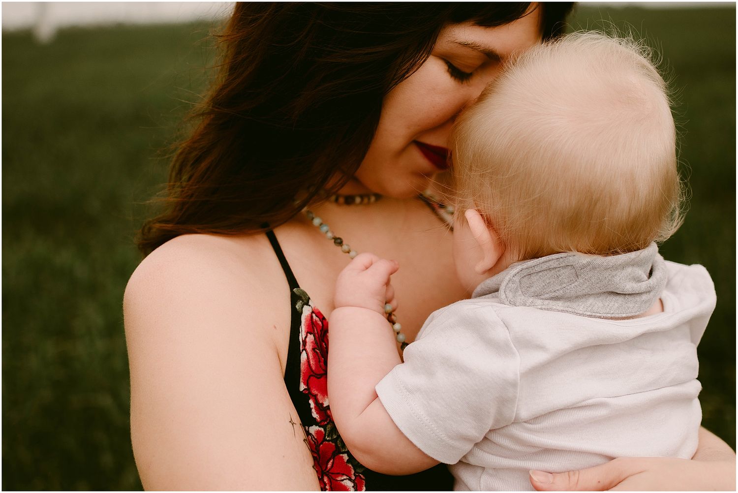 Intimate close-up of nurturing moment between adult and baby in outdoor setting.